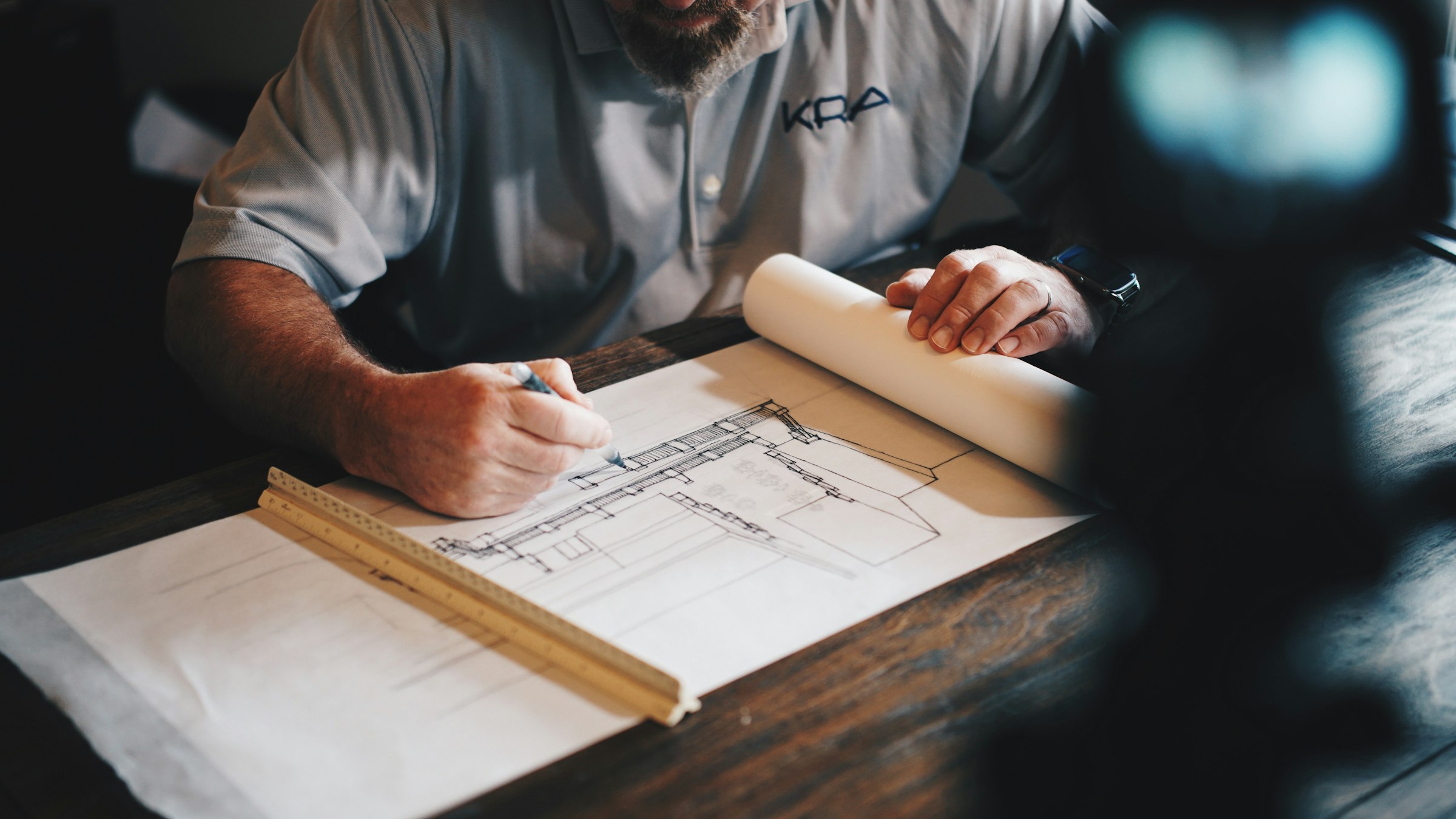 Arquitecto revisando a mano un plano de sección constructiva sobre una mesa de trabajo.